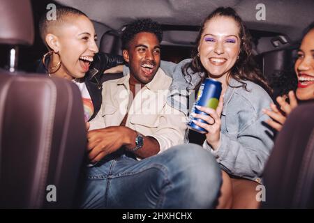 S'amuser sur la banquette arrière. Groupe de quatre amis heureux qui rient ensemble tout en s'asseyant ensemble à l'arrière d'une voiture. Des amis insouciants qui ont un bon séjour moi Banque D'Images