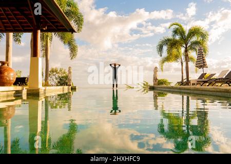 Un homme debout au bord de la piscine à débordement Banque D'Images