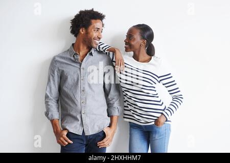 Absolument smitten. Un jeune couple heureux debout ensemble affectueusement contre un mur blanc. Banque D'Images