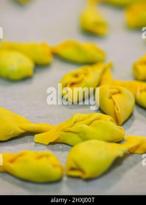 Les femmes chefs préparent les tortelli italiens farcis passé avec le fromage ricotta et les spinachs avec la pâte d'oeufs bio dans une cuisine professionnelle en Italie Banque D'Images