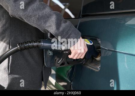 Un jeune homme méconnaissable met du carburant dans la voiture. Banque D'Images