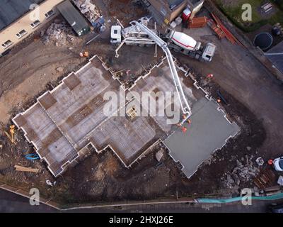 Les ouvriers sur place à la construction de la maison, versant la couche de béton de base d'un mélangeur via une pompe hydraulique Banque D'Images