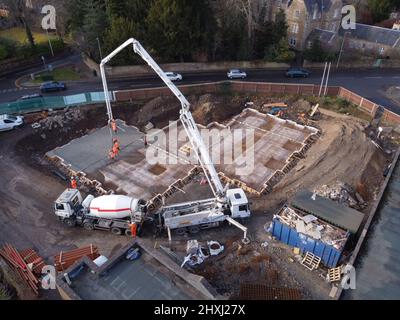 Les ouvriers sur place à la construction de la maison, versant la couche de béton de base d'un mélangeur via une pompe hydraulique Banque D'Images