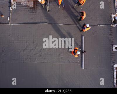 Les ouvriers sur place à la construction de la maison, versant la couche de béton de base d'un mélangeur via une pompe hydraulique Banque D'Images