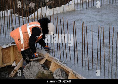 Les ouvriers sur place à la construction de la maison, versant la couche de béton de base d'un mélangeur via une pompe hydraulique Banque D'Images