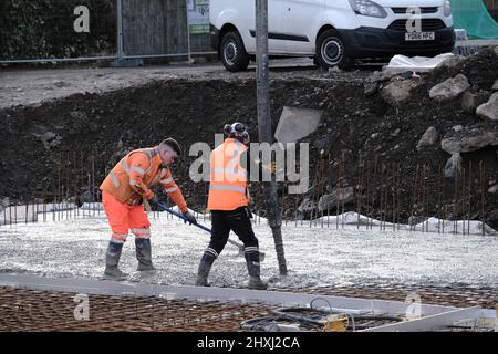 Les ouvriers sur place à la construction de la maison, versant la couche de béton de base d'un mélangeur via une pompe hydraulique Banque D'Images