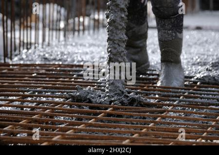 Les ouvriers sur place à la construction de la maison, versant la couche de béton de base d'un mélangeur via une pompe hydraulique Banque D'Images