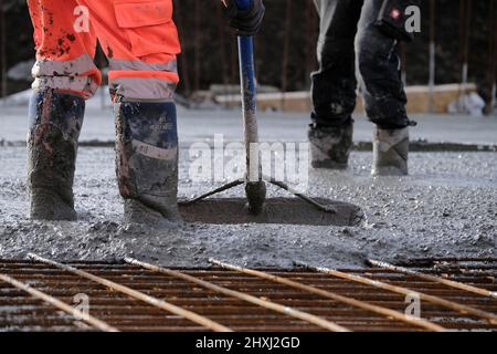 Les ouvriers sur place à la construction de la maison, versant la couche de béton de base d'un mélangeur via une pompe hydraulique Banque D'Images