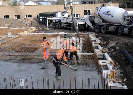 Les ouvriers sur place à la construction de la maison, versant la couche de béton de base d'un mélangeur via une pompe hydraulique Banque D'Images