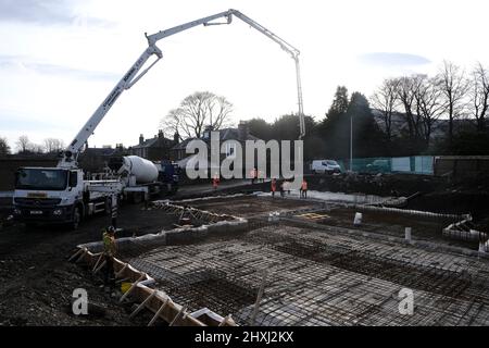 Les ouvriers sur place à la construction de la maison, versant la couche de béton de base d'un mélangeur via une pompe hydraulique Banque D'Images