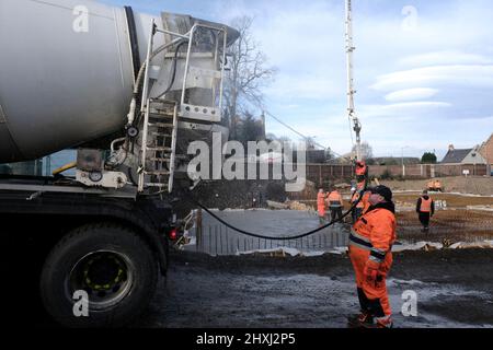 Les ouvriers sur place à la construction de la maison, versant la couche de béton de base d'un mélangeur via une pompe hydraulique Banque D'Images