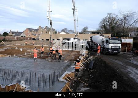 Les ouvriers sur place à la construction de la maison, versant la couche de béton de base d'un mélangeur via une pompe hydraulique Banque D'Images