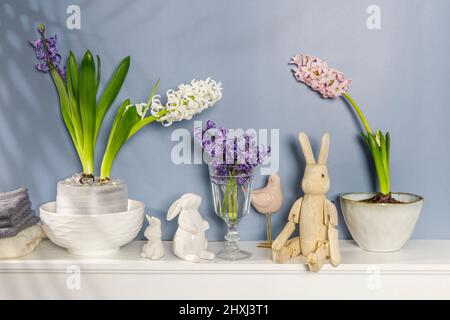 Jacinthe blanche dans un grand bol en porcelaine, figurines de lièvres et un oiseau, sont sur la cheminée contre le mur bleu foncé. Mise en page. Concept de ressort Banque D'Images