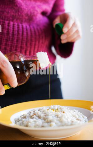 Ajouter un peu d'huile d'olive au porridge. Mise au point sélective et faible profondeur de champ. Banque D'Images