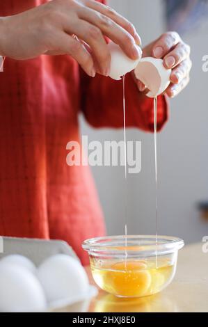 Préparer la nourriture, les mains craquer un œuf cru. Banque D'Images