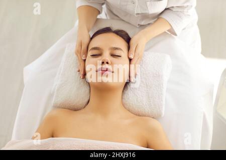 Calme belle femme aime le massage relaxant du visage donné à elle par spécialiste en spa. Banque D'Images