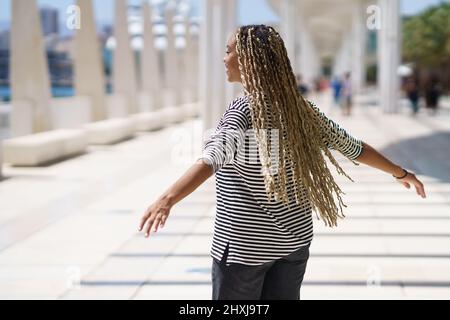 Jeune femme noire déplaçant ses tresses colorées dans le vent.Style africain typique. Banque D'Images