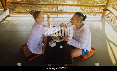 Un jeune homme et une femme séduisants mangent et boivent des boissons savoureuses en passant du temps dans un café flottant local traditionnel sur l'eau.J'aime un couple heureux qui a du bre Banque D'Images