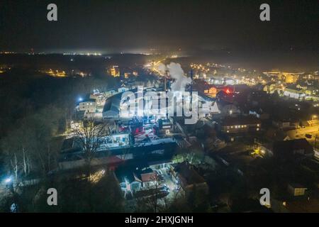 Fait d'une grande hauteur, un panorama d'une petite ville provinciale à l'aide d'un drone. Une usine très éclairée est visible au centre du châssis. Banque D'Images