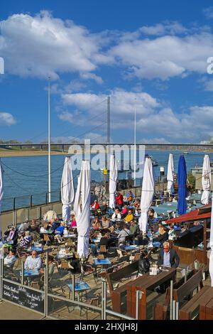 Düsseldorf (Rheinpromenade), Allemagne - mars 9. 2022: Vue sur le rhin restaurant café avec des personnes assis dehors le jour d'hiver ensoleillé Banque D'Images