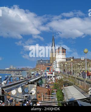 Düsseldorf (Rheinpromenade), Allemagne - mars 9. 2022: Vue sur la promenade au bord de la rivière, cafés-restaurants en plein air avec ciel bleu d'hiver sur le château médiéval Banque D'Images