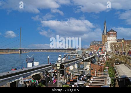 Düsseldorf (Rheinpromenade), Allemagne - mars 9. 2022: Vue sur la promenade au bord de la rivière, cafés-restaurants en plein air avec ciel bleu d'hiver sur le château médiéval Banque D'Images