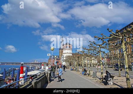 Düsseldorf (Rheinpromenade), Allemagne - mars 9. 2022: Vue au-delà des arbres sycomore sur la promenade du Riversider, tour du château historique, arrière-plan de l'église o Banque D'Images