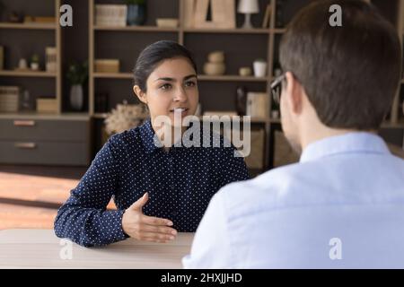 Une femme indienne parle avec un partenaire d'affaires masculin à la table de négociation Banque D'Images