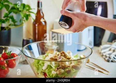 Femme prépare une salade de légumes verts dans un bol en verre à la cuisine, concept de saine alimentation et de régime Banque D'Images