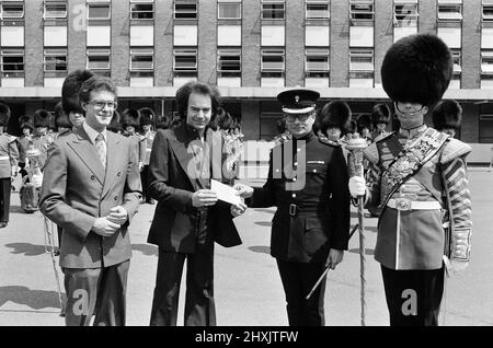 L'animateur Neil Diamond et Lord Tavistock présentent un chèque au bataillon du 2nd, Grenadier Guards, à la caserne Chelsea. Le chèque a été un « merci » pour la performance du corps des tambours au début du concert de samedi dernier à l'abbaye de Woburn, lorsque Diamond a joué à plus de 51 000 personnes. Il sera remis aux Fonds de la Division des ménages (appel du Jubilé d'argent), et est le produit de la vente des programmes Neil Diamond au concert. 7th juillet 1977. Banque D'Images