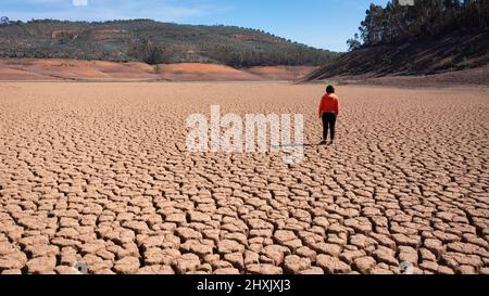 Silhouette d'un homme sur une terre sablonneuse craquée vide non fertile pendant une sécheresse. Le concept de catastrophe écologique sur la planète. Banque D'Images