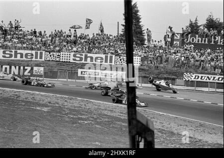 James Hunt (à l'extrême droite de la McLaren Texeco) se bloque mais après un redémarrage, gagne toujours en 1976 le Grand Prix britannique à Brands Hatch. Le conducteur britannique James Hunt a été impliqué dans un premier accident de virage qui a provoqué l'apparition des drapeaux rouges. Hunt a conduit sa voiture endommagée vers les fosses, mais n'a pas terminé un tour complet de la piste pour le faire, au lieu de conduire à travers une route d'accès sur la Cooper Straight. Les responsables ont déclaré que, puisqu'il n'avait pas été sur le circuit lorsque le drapeau rouge était agité, Hunt ne serait pas autorisé à prendre part au redémarrage. Cette nouvelle a provoqué un sentiment de colère parmi les BR Banque D'Images