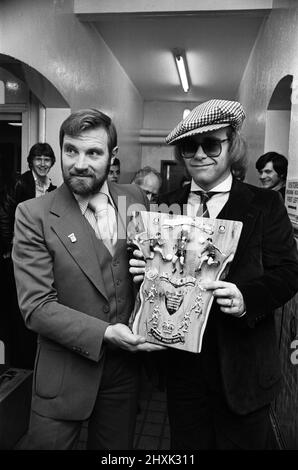 Elton John, musicien et président du FC Watford, reçoit une plaque spéciale Jubilé qui lui est présentée par Ray Egan, fan de West Bromwich Albion. C'était une consolation pour Elton après la défaite de 1-0 par Albion lors de l'affrontement de la coupe de la Ligue de football aux Hawthorns. 25th octobre 1977. Banque D'Images