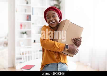 Jeune femme noire ecstatique qui garde la boîte à la maison Banque D'Images