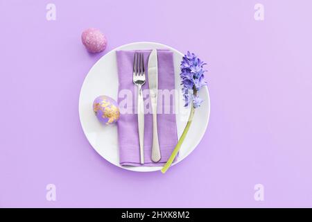 Belle table avec œufs de Pâques et fleurs sur fond lilas Banque D'Images