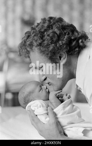 Joe Bugner, ancien boxeur européen britannique à poids lourd, embrasse son nouveau fils Lajos James après sa naissance à l'hôpital de maternité de Hill Road à Cambridge. 16th mai 1976. Banque D'Images