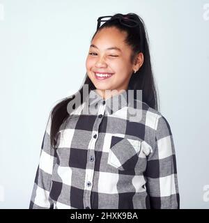 Décaler à-coup, tordre. Portrait studio d'une jeune fille mignonne et confiante posant sur un fond gris. Banque D'Images