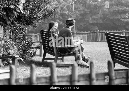 Bien dans le 80s - le soleil d'aujourd'hui a amené des gens sur Hampstead Heath, Londres, pour se rafraîchir. Deux religieuses s'assoient en profitant du temps, il est devenu trop chaud pour l'un d'eux et elle a hissé son habitude sur sa tête. 8th mai 1976. Banque D'Images