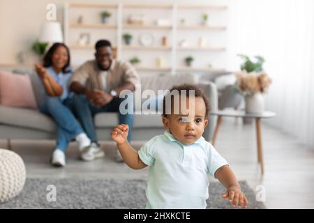 Bébé noir marchant dans le salon faisant les premiers pas Banque D'Images