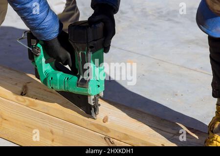 Constructeur à l'intérieur de bois homme en clouant des poutres en bois travaux de construction à l'aide d'un marteau pneumatique Banque D'Images