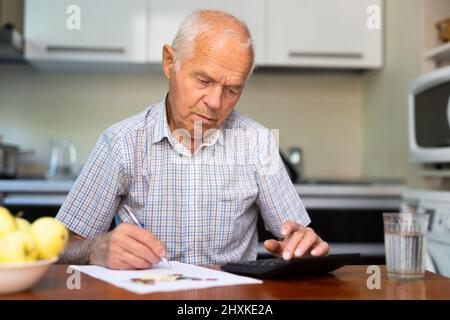 L'homme assis à table à la maison le calcul de leurs finances et leurs factures domestiques Banque D'Images