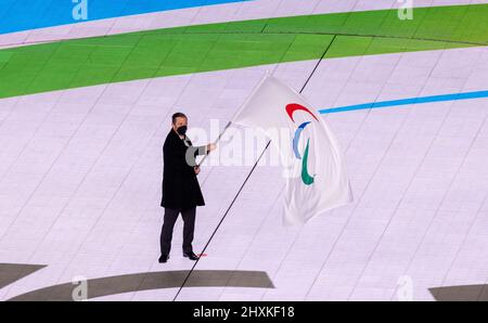 13 mars 2022, Chine, Pékin : Paralympiques : cérémonie de clôture au stade olympique 'Bird's Nest'. Andrew Parsons, président du Comité paralympique international, fait passer le drapeau paralympique avant du remettre en Italie. La cérémonie de clôture marque la fin des Jeux paralympiques d'hiver à Beijing, la capitale de la Chine. Photo: Jens Büttner/dpa-Zentralbild/dpa Banque D'Images