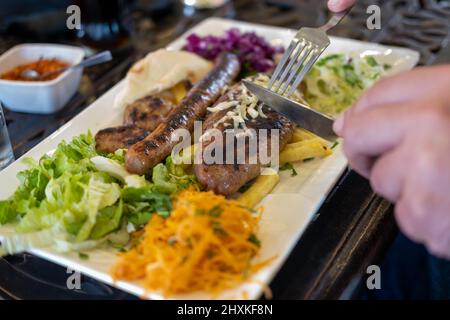 Différents types de viande grillée ou barbecue sur l'assiette, en coupant et en coupant des boulettes de viande avec du fromage et des saucisses avec salade de légumes et frites Banque D'Images