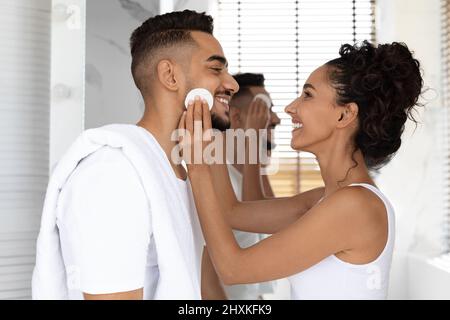Portrait d'un couple arabe heureux faisant la routine de beauté dans la salle de bains ensemble Banque D'Images