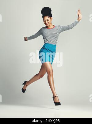 Partez à la conquête de vos rêves avec Bien sûr. Photo en studio d'une jeune femme à la mode se posant sur un fond gris. Banque D'Images