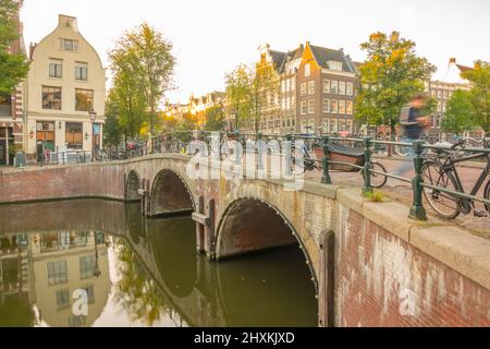 Pays-Bas. Pont en pierre avec trois arches sur le canal d'Amsterdam. Beaucoup de vélos garés. Matin avec les premiers rayons du soleil Banque D'Images