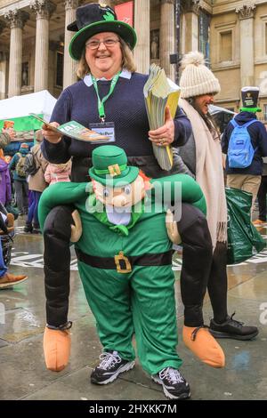 Londres, Royaume-Uni. 13th mars 2022. Une femme qui distribue des programmes de festival garde son esprit pendant l'après-midi pluvieux. Les participants et les spectateurs s'amusent au défilé du maire de Londres à la Saint-Patrick dans le centre de Londres avec des groupes de marche, des danseurs et des fanfares, malgré le temps. Il y a aussi une scène, des stands et des spectacles sur Trafalgar Square. Credit: Imagetraceur/Alamy Live News Banque D'Images