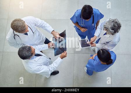 Travailler ensemble pour maintenir leur niveau de qualité de soins de santé. Prise de vue en grand angle d'un groupe de médecins travaillant ensemble dans un hôpital. Banque D'Images