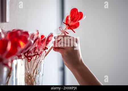 Des sucettes rouges en forme de cœur sur le comptoir d'un magasin de bonbons. Banque D'Images