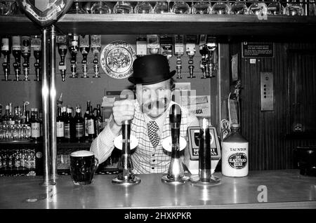 Bobby Moore se prépare à l'ouverture de sa propre maison publique appelée Moore's à Stratford Broadway, dans l'est de Londres. Il porte un chapeau de melon et une fausse moustache. Bobby Moore joue à Flo Fulham en ce moment. Photo prise le 17th novembre 1976 Bobby Moore se préparant à l'ouverture de sa propre maison publique appelée Moore's à Stratford Broadway, Londres est. Il porte un chapeau de melon et une fausse moustache. Bobby Moore joue pour Fulham à ce moment. Photo prise le 17th novembre 1976 Banque D'Images